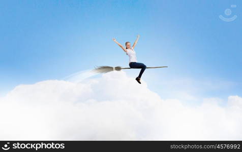 Young and careless. Happy young woman flying in sky on broom