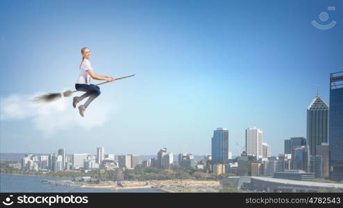 Young and careless. Happy young woman flying in sky on broom