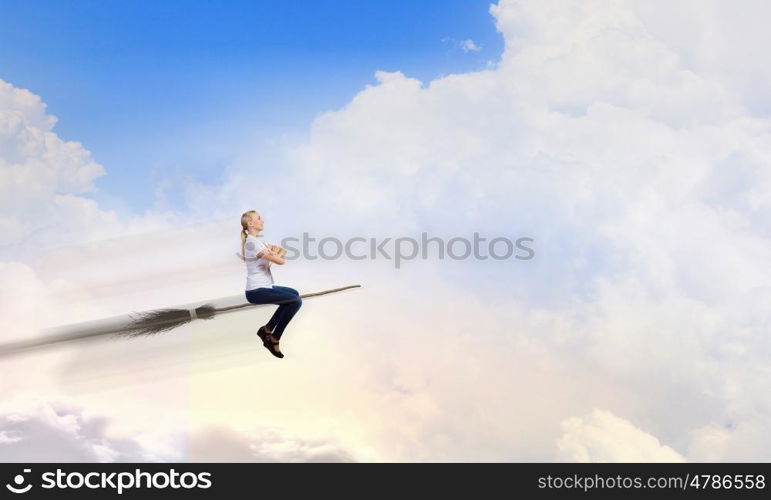 Young and careless. Happy young woman flying in sky on broom