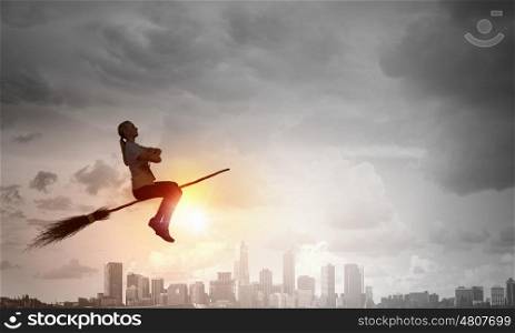 Young and careless. Happy young woman flying in sky on broom
