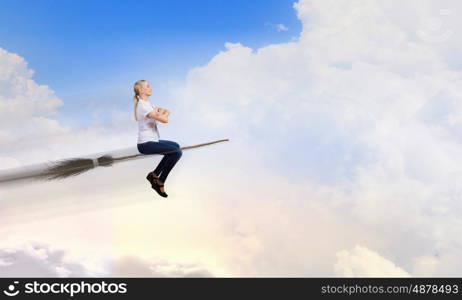 Young and careless. Happy young woman flying in sky on broom