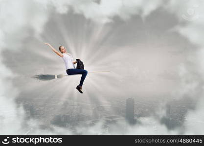 Young and careless. Happy young woman flying in sky on broom