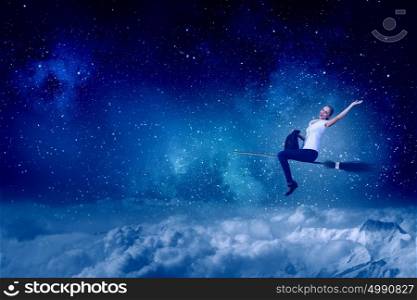 Young and careless. Happy young woman flying in sky on broom