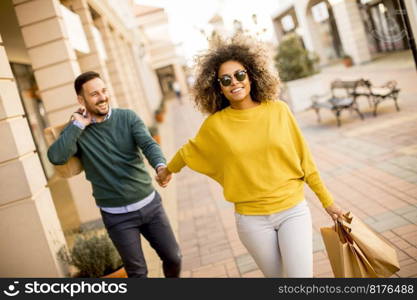 Young and cheerfull couple walking along street with shopping bags