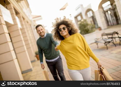 Young and cheerfull couple walking along street with shopping bags