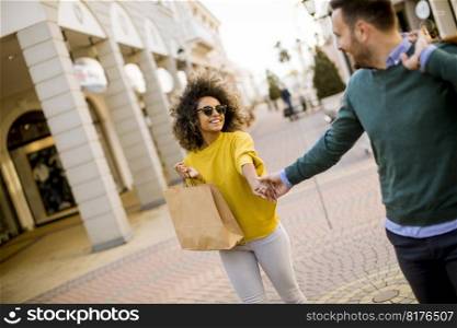 Young and cheerfull couple walking along street with shopping bags