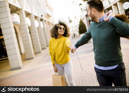 Young and cheerfull couple walking along street with shopping bags