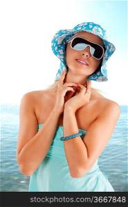 young and cute woman with sunglasses pushing hat against head