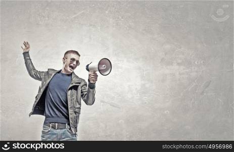 Young and emotional. Young man in casual screaming emotionally in megaphone