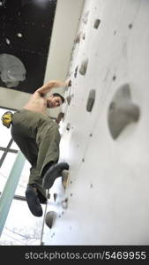 young and fit man exercise free mountain climbing on indoor practice wall