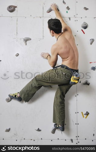 young and fit man exercise free mountain climbing on indoor practice wall