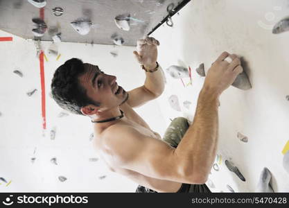 young and fit man exercise free mountain climbing on indoor practice wall