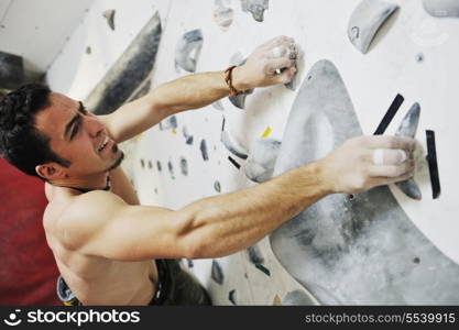 young and fit man exercise free mountain climbing on indoor practice wall