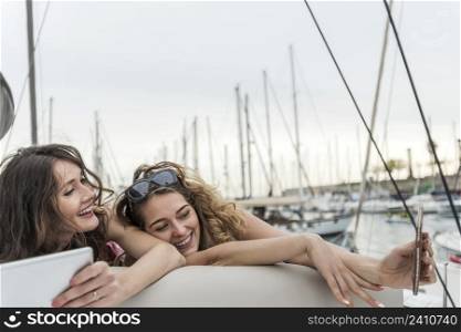 young and happy girl friends laying together on a sail boat