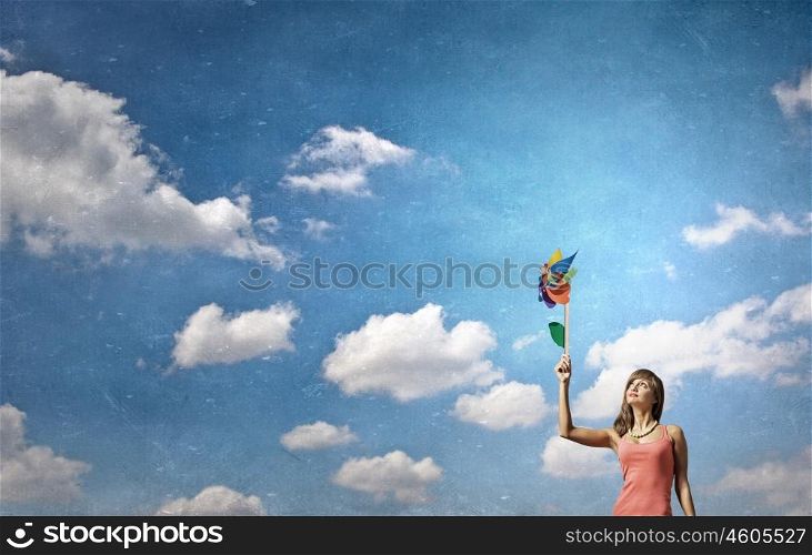 Young and happy. Happy young woman with windmill in hand