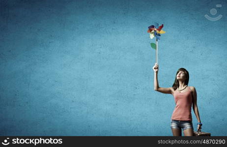 Young and happy. Happy young woman with windmill in hand