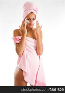 young and pretty girl with pink towel spreading on cream and making face