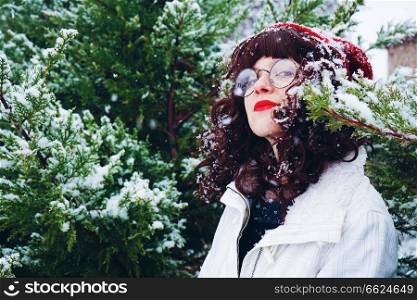 Young and pretty woman enjoying a snowy winter day surrounded by trees