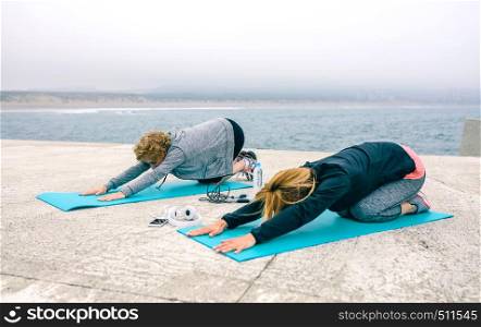 Young and senior woman stretching back outdoors by sea pier. Young and senior woman stretching back outdoors