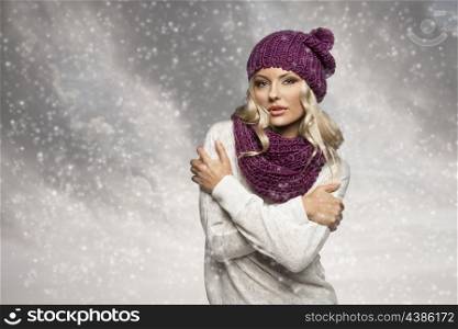 young and sexy blond girl wearing purple scarf and hat in winter dress over white