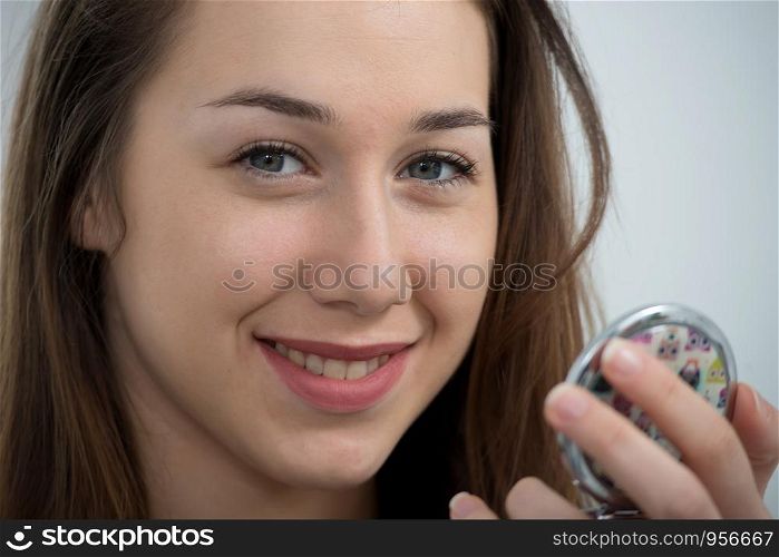 young and smiling woman putting a lipstick