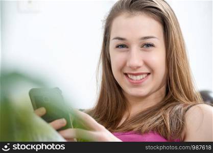 young and smiling woman using a smartphone at home