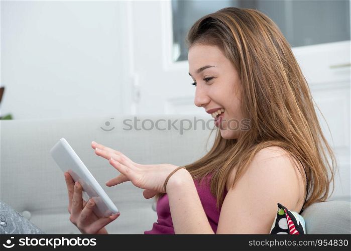 young and smiling woman using a tablet on the sofa