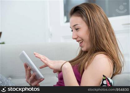 young and smiling woman using a tablet on the sofa
