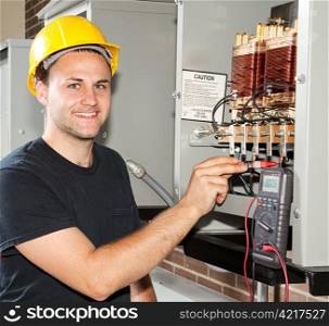 Young apprentice electrician measures power coming through coils of an industrial power distribution center.