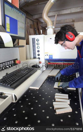 Young apprentice measuring a piece of wood