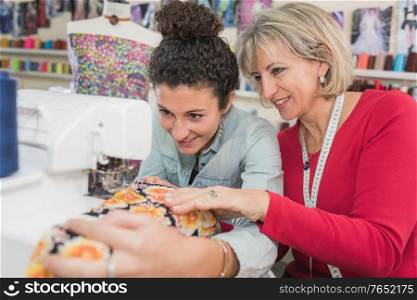 young apprentice woman making a dress with boss