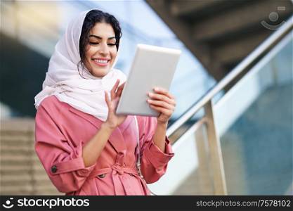 Young Arab woman wearing hijab headscarf using digital tablet in business environment. Young Arab woman wearing hijab using digital tablet outdoors
