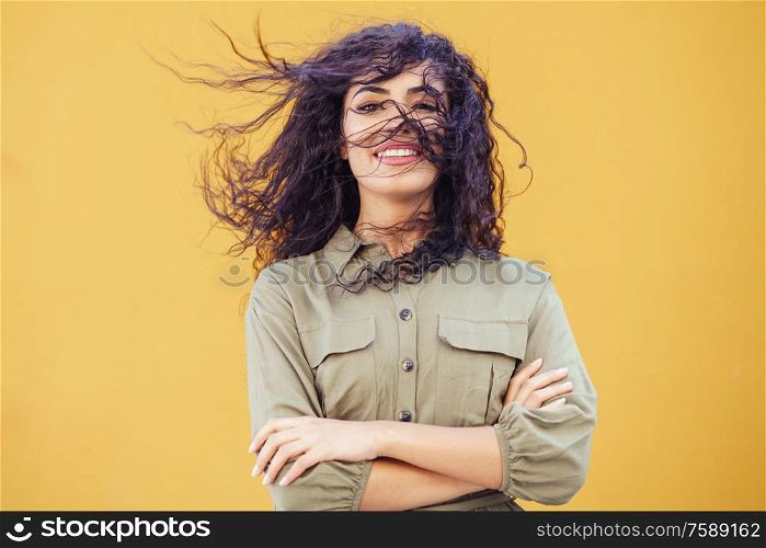 Young Arab Woman with curly hair in her face on urban yellow wall. Arab Woman with curly hair in her face