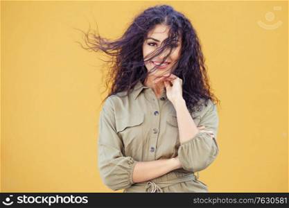Young Arab Woman with curly hair in her face on urban yellow wall. Arab Woman with curly hair in her face