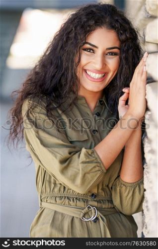 Young Arab Woman with curly hair laughing in urban background. Happy Arab Woman with curly hair outdoors