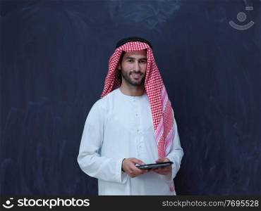 young arabian muslim businessman using tablet computer wearing hijab clothes in front of black chalkboard