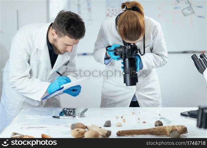 Young archaeology researchers document lithics with camera in laboratory.. Archaeology Researchers in Laboratory, Documenting Artifacts with Camera