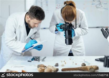 Young archaeology researchers document lithics with camera in laboratory.. Archaeology Researchers in Laboratory, Documenting Artifacts with Camera