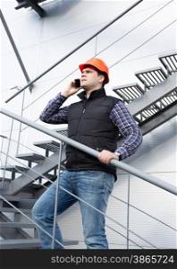 Young architect talking on phone while inspecting factory