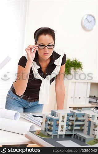Young architect with glasses working at modern office with architectural model