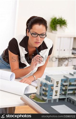 Young architect with glasses working at modern office with architectural model