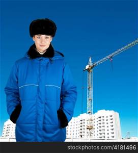 Young architect-woman wearing protective winter cloth standing on the building background