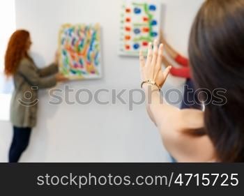 Young artists in gallery hanging painting on walls. Young artists in gallery hanging together painting on walls
