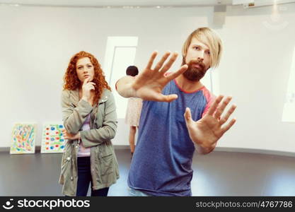 Young artists in gallery hanging painting on walls. Young artists in gallery hanging together painting on walls