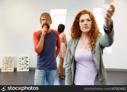 Young artists in gallery hanging painting on walls. Young artists in gallery hanging together painting on walls