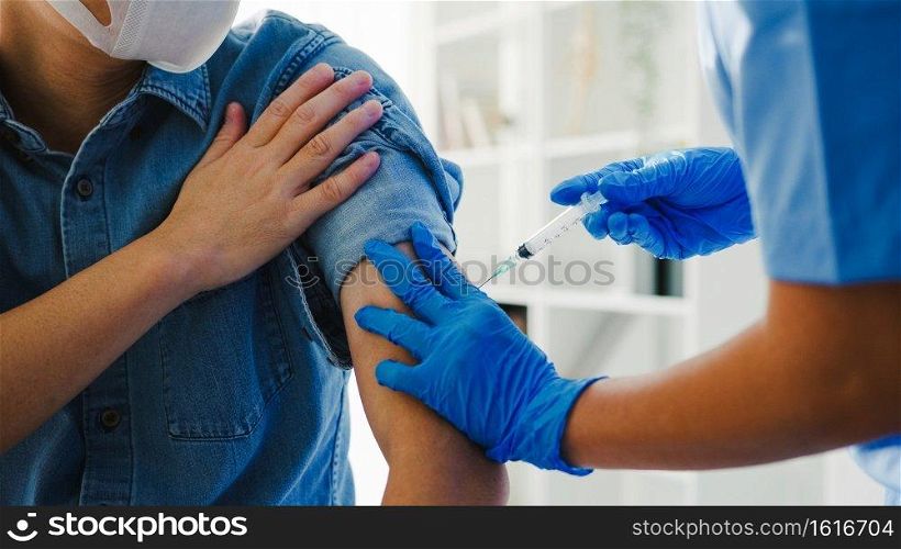 Young Asia lady nurse giving Covid-19 or flu antivirus vaccine shot to senior male patient wear face mask protection from virus disease at health clinic or hospital office. Vaccination concept.