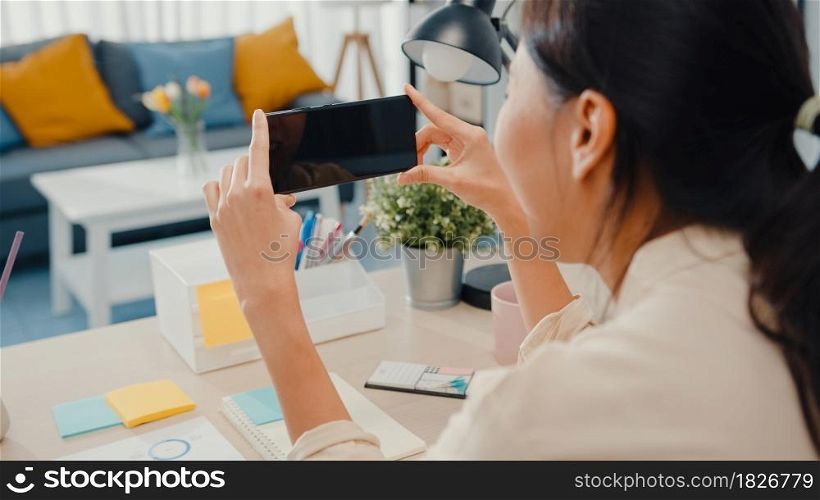 Young Asia lady use smart phone with blank black screen mock up display for advertising text while smart working from home at living room. Chroma key technology, Marketing design concept.