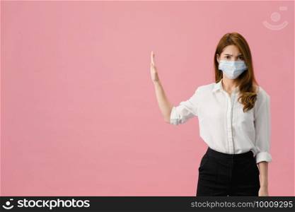 Young Asia lady wear medical face mask doing stop sing with palm of hand with negative expression and looking at camera isolated on blue background. Social distancing, quarantine for corona virus.