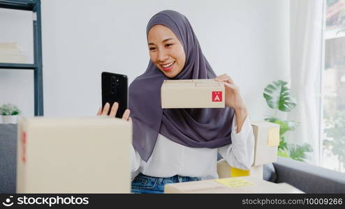 Young Asia muslim businesswoman blogger using mobile phone camera to recording vlog video live streaming review product at home office. Small business owner, start up online market delivery concept.