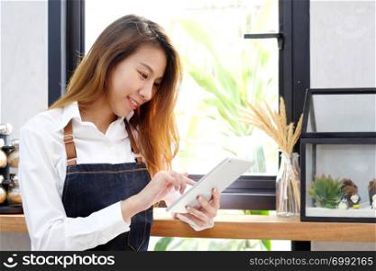 Young asia woman, barista, using tablet at cafe counter background, food and drink concept